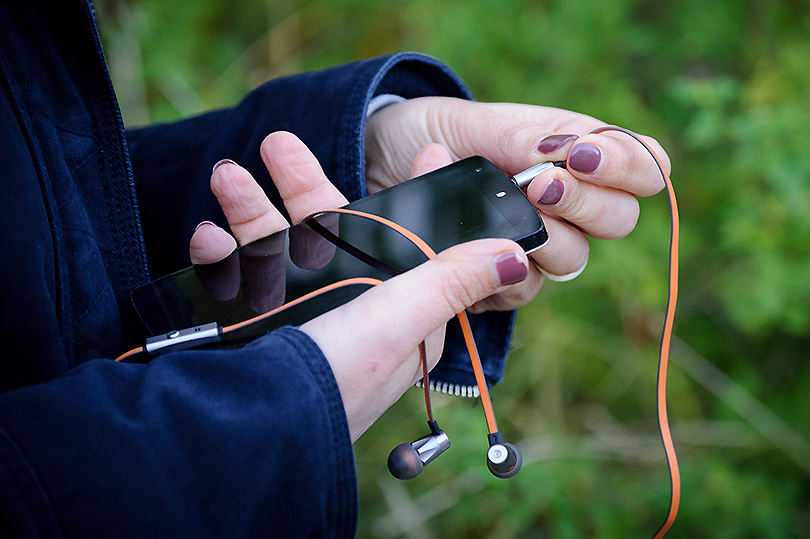 Particulier utilisant un kit mains libres sur son téléphone portable pour s'éloigner des ondes électromagnétiques